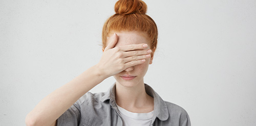 Eine Frau die sich die Hand vor ihr Gesicht hält